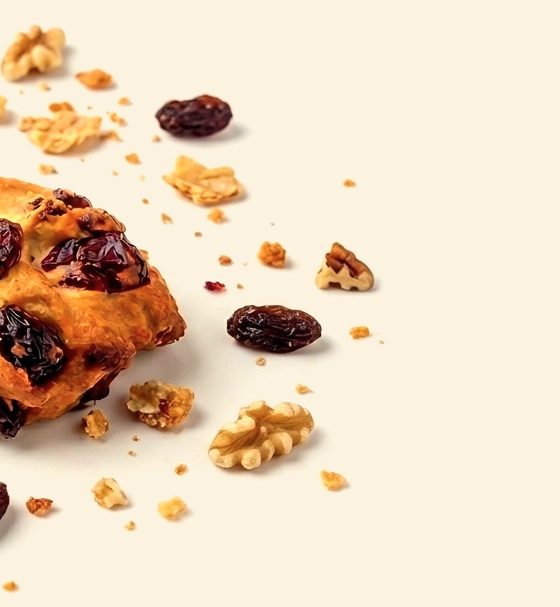 Raisins, walnuts and pecans scattered beside a pastry bite
