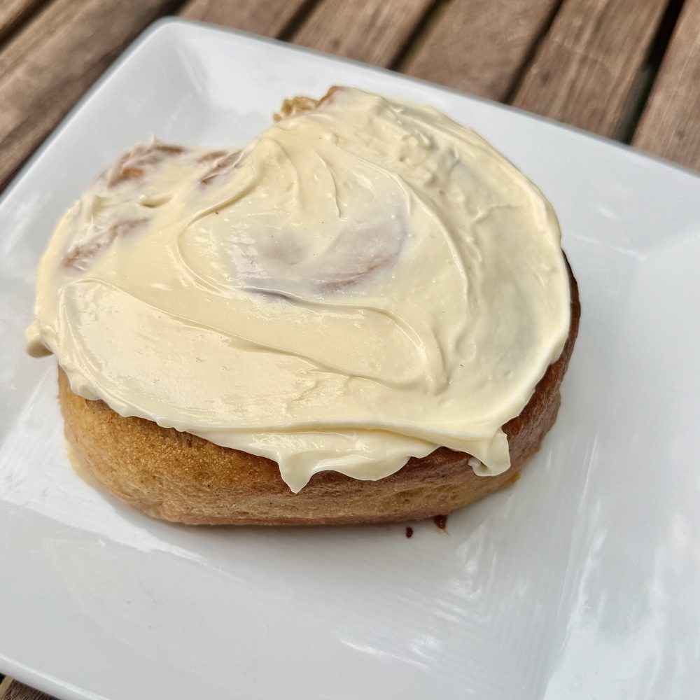 A pumpkin cinnamon roll, the pumpkin colour showing in the crumb
