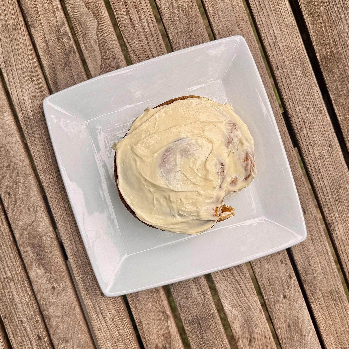 A sourdough pumpkin cinnamon roll with cream cheese frosting on a white plate