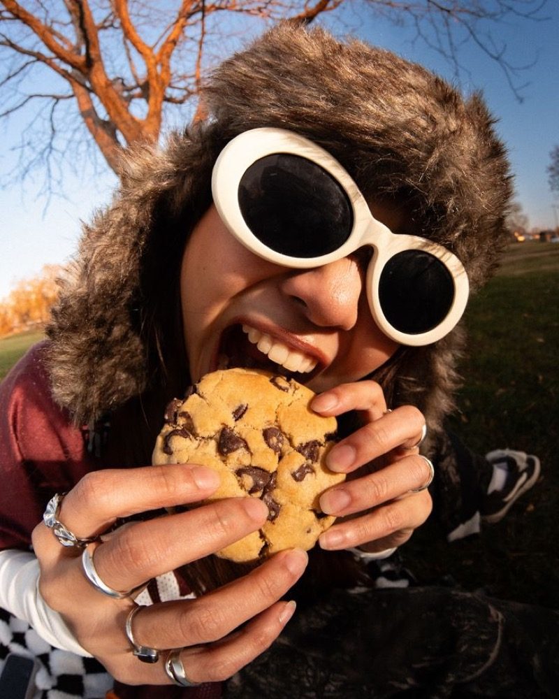 A young woman with a pastry under autumn trees