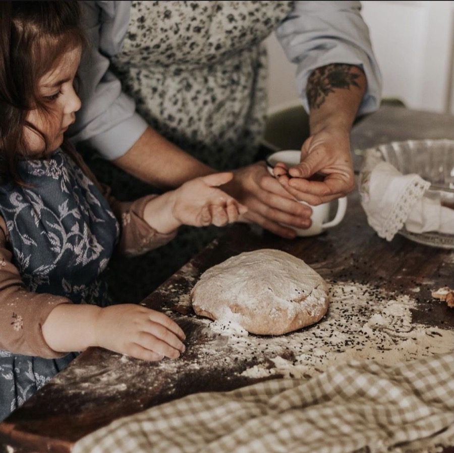 Two pairs of hands working dough on a floured board