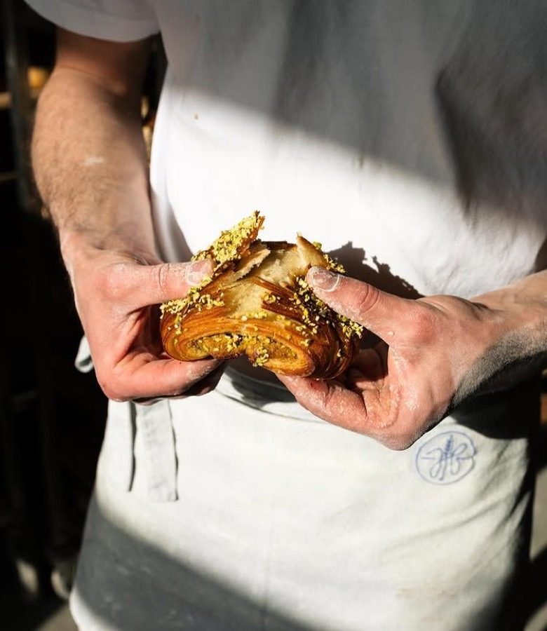 A baker holding a warm pastry in both hands